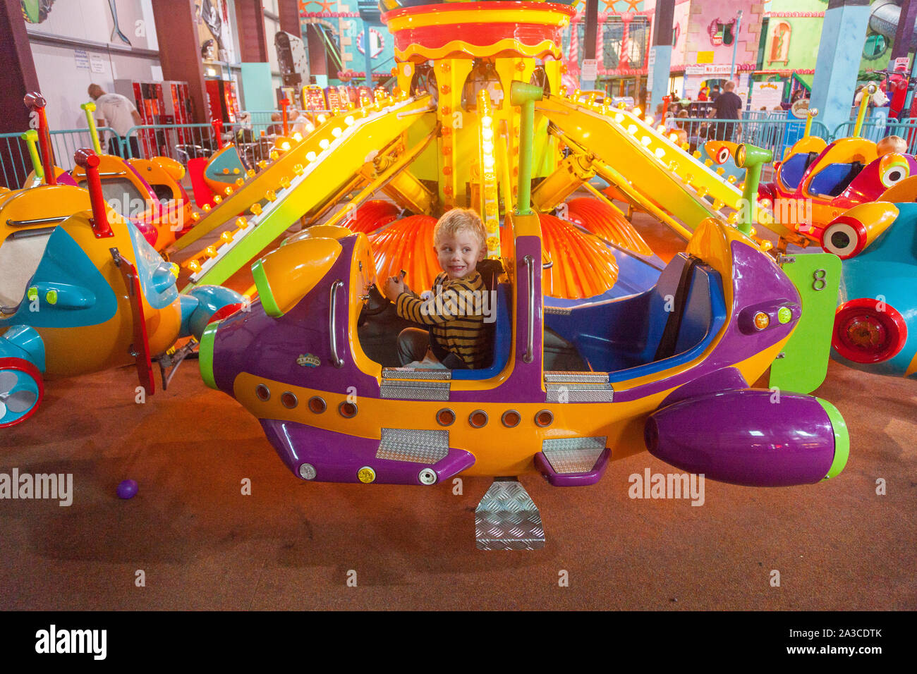 Two year old boy on a fairground ride at Woodlands Family Theme Park, Totnes, Devon, England