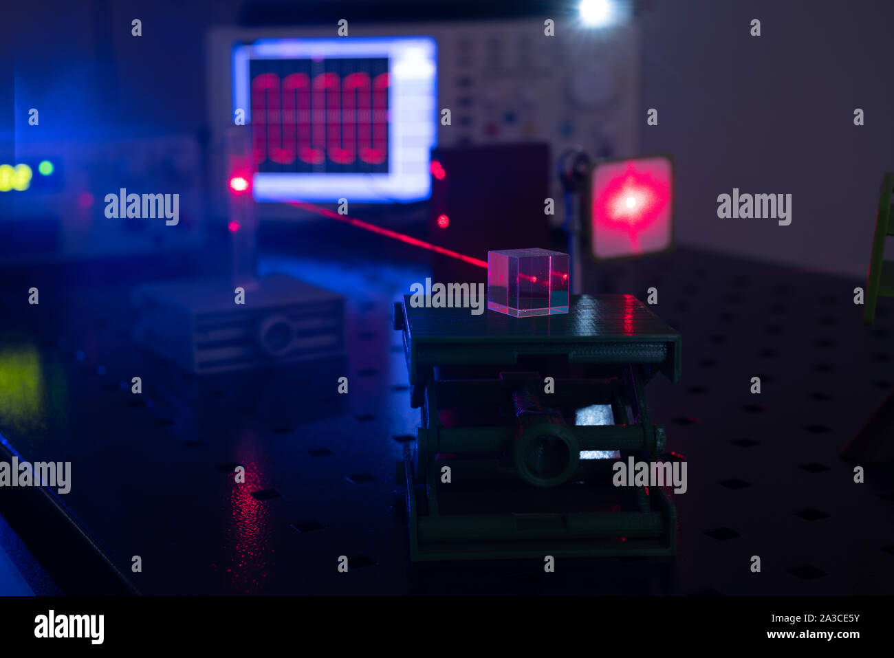 Experiment in optic lab with laser device. Red laser on optical table ...