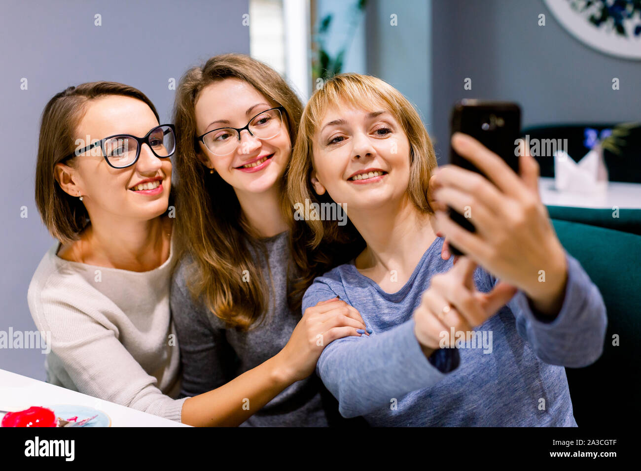 Three beautiful young women enjoying coffee and cake together in a cafe ...