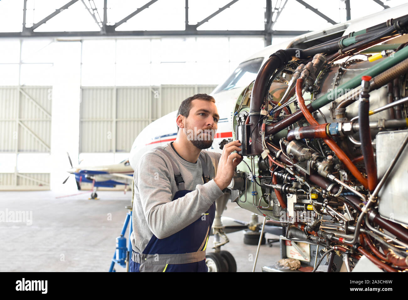 Aircraft mechanic repairs an aircraft engine in an airport hangar Stock Photo