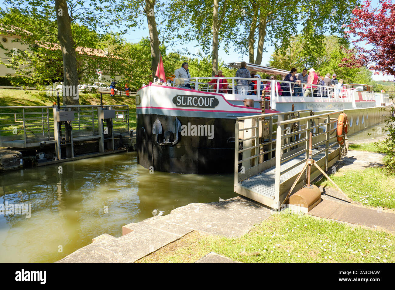 The Surcouf tourist cruise flat boat in the Emborrel Locks on the Canal du Midi passing the open gates opens it to continue travel on the canal Stock Photo