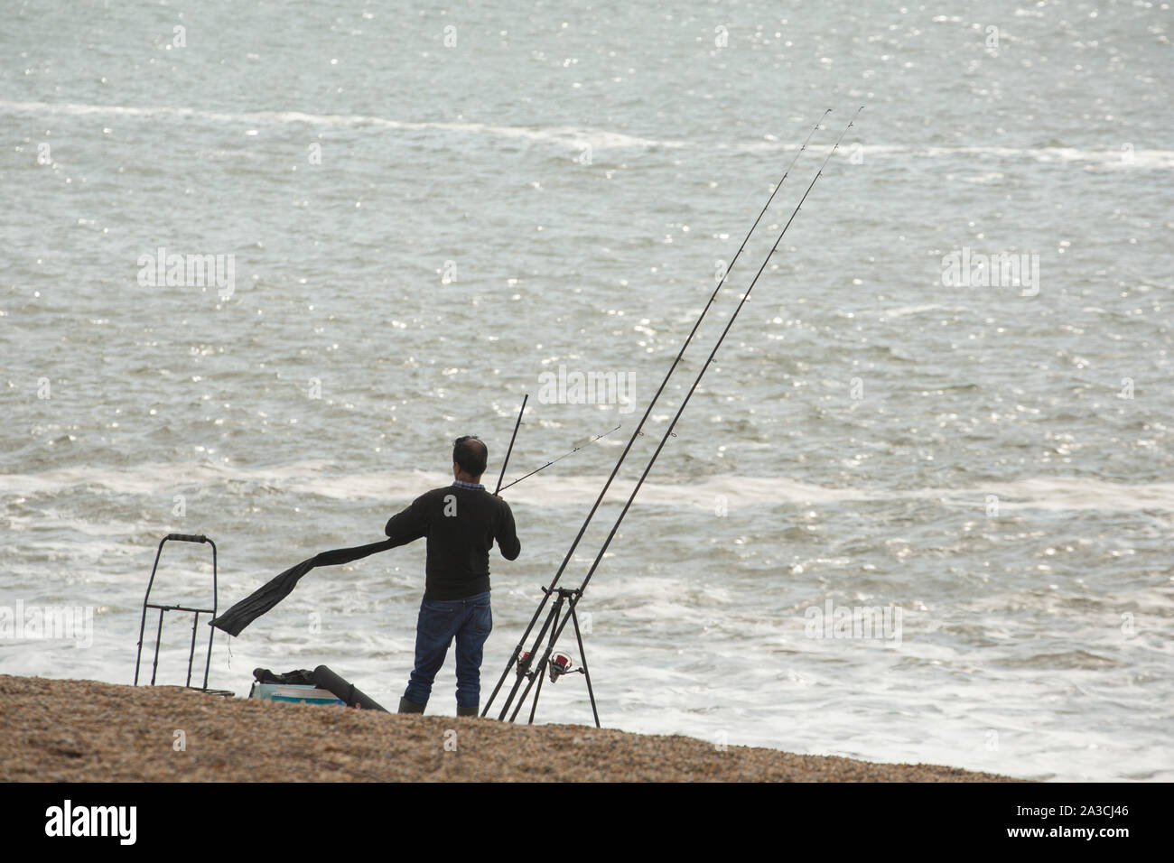 An angler fishing on Chesil beach in October the day after a storm when