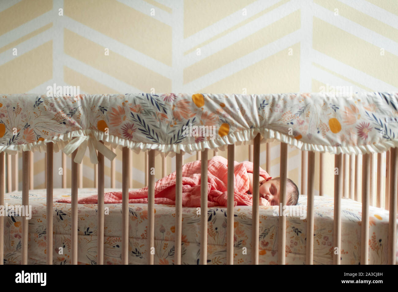 Newborn Baby Girl Wrapped Up In Blanket Sleeping In Her Crib At