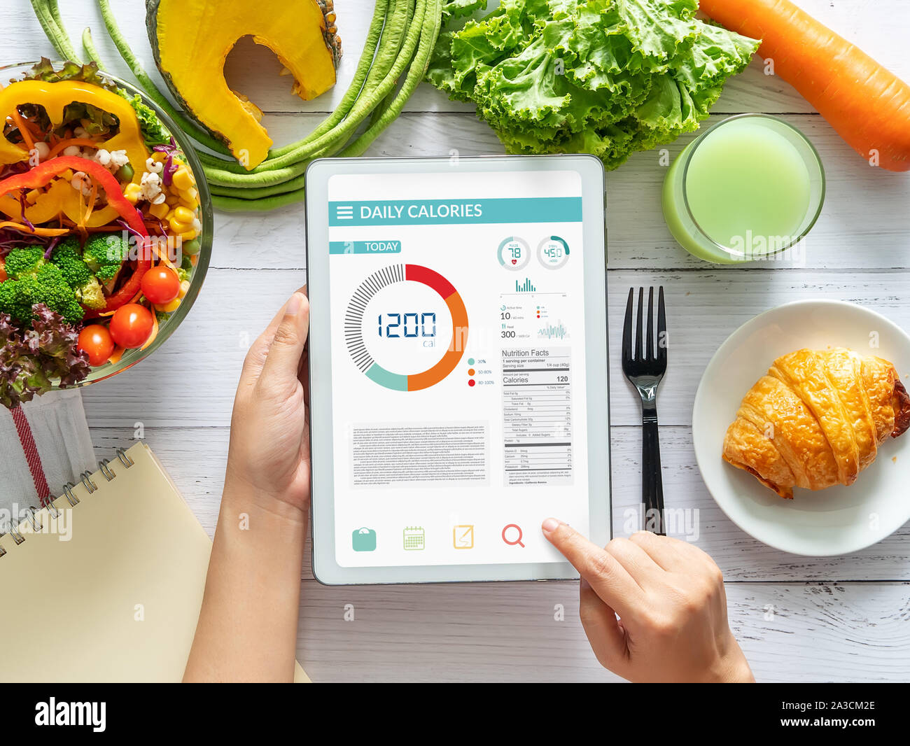 Calories counting , diet , food control and weight loss concept. woman using Calorie counter application on tablet at dining table with fresh vegetabl Stock Photo