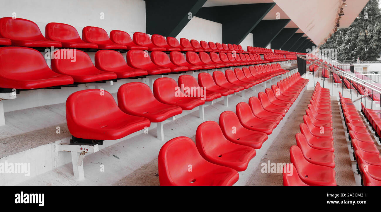 side view of empty red plastic seats row at football sport stadium. stadium seats background Stock Photo