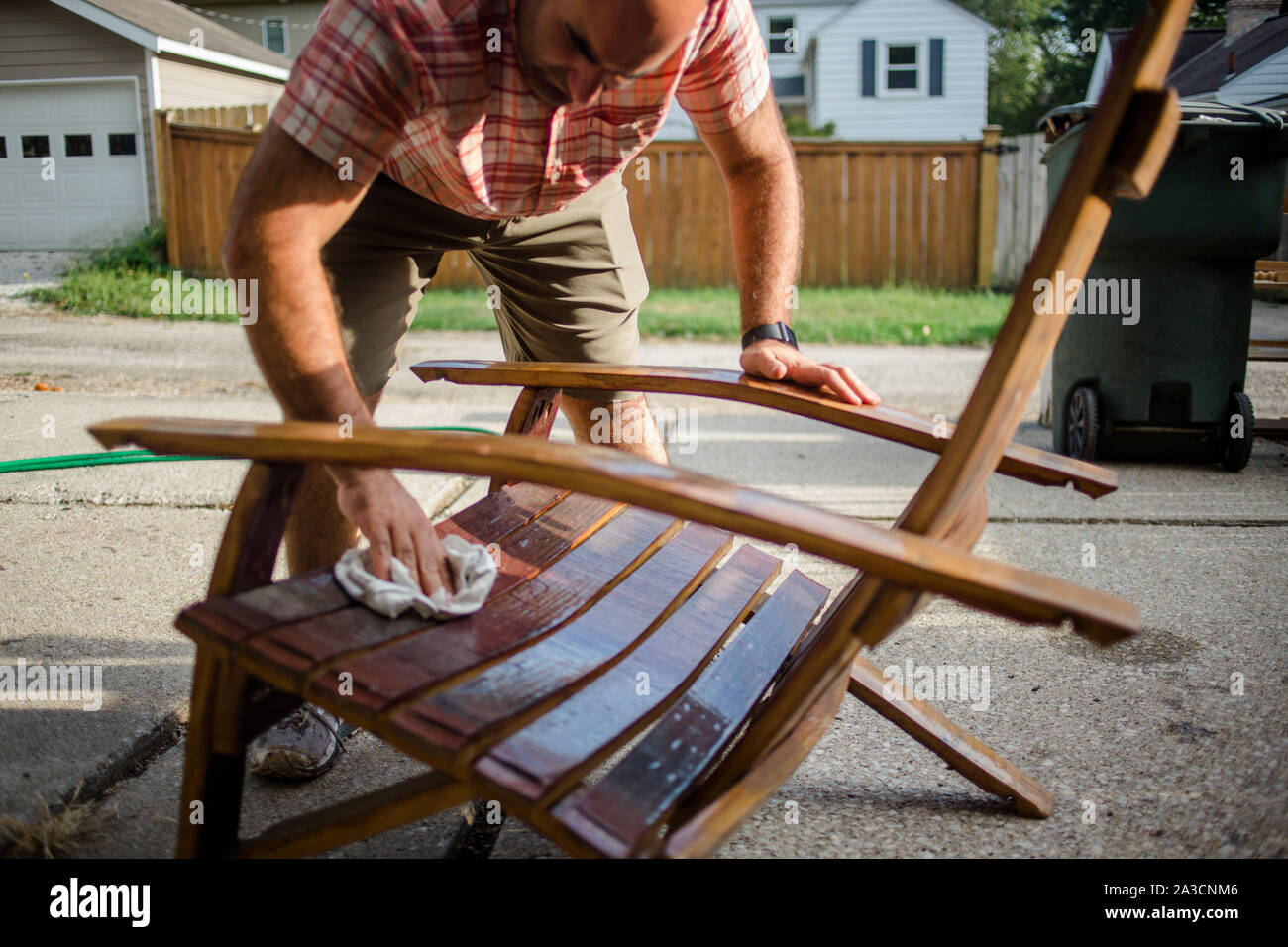 A craftsman polishes a handmade wooden chair outside Stock Photo