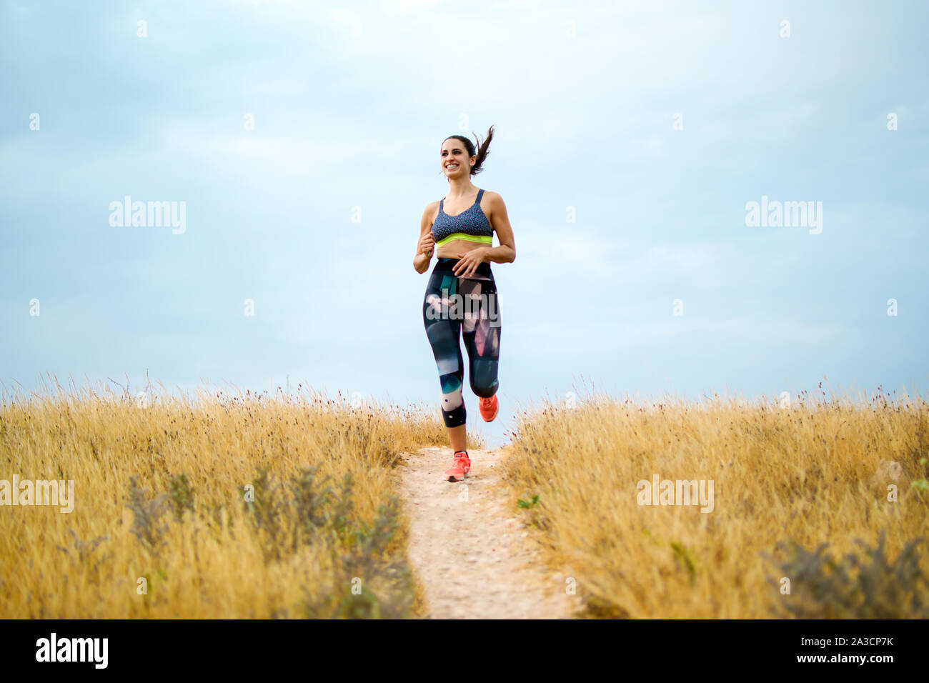 Young caucassian sportswoman running on the countryside exercising on summer Stock Photo