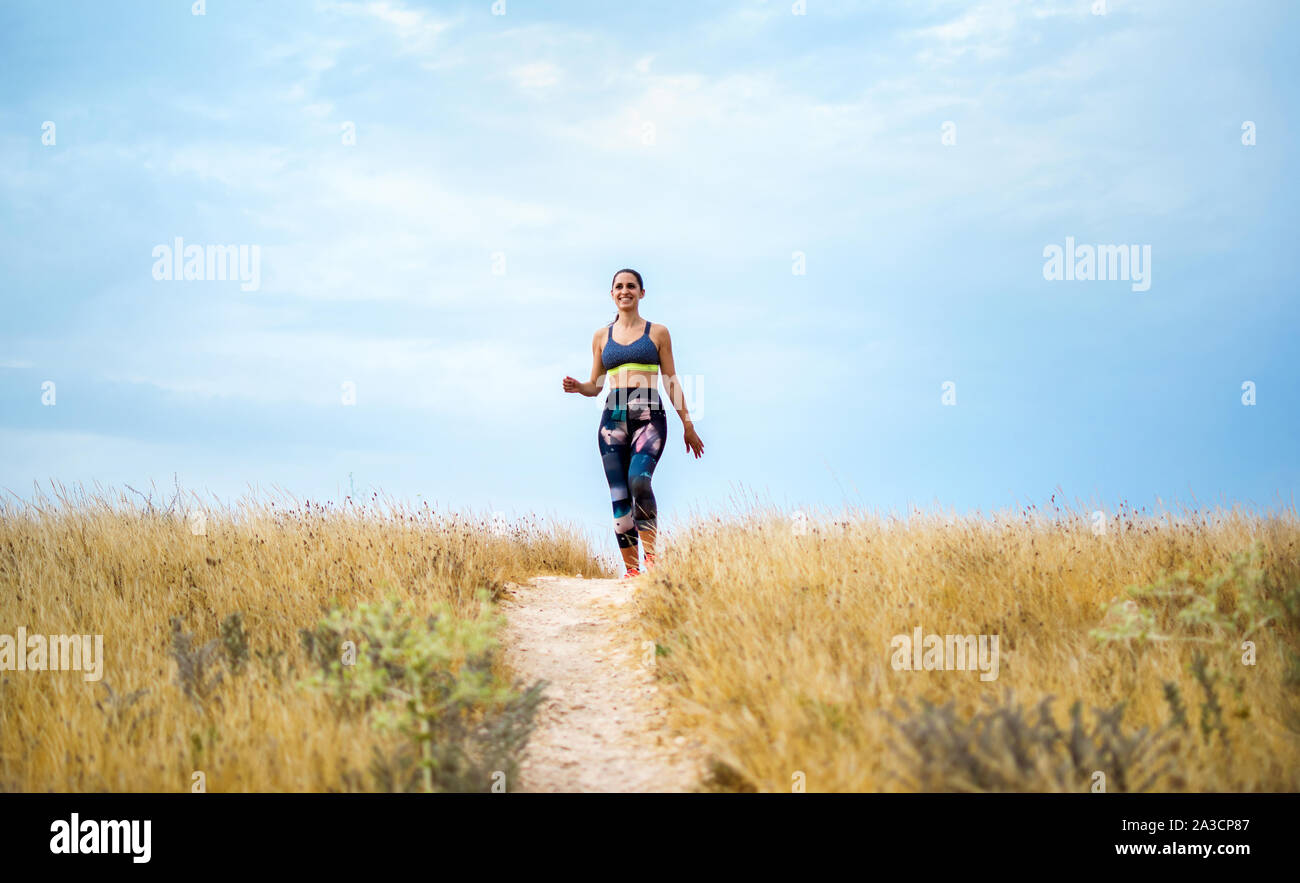 Young caucassian sportswoman running on the countryside exercising on summer Stock Photo