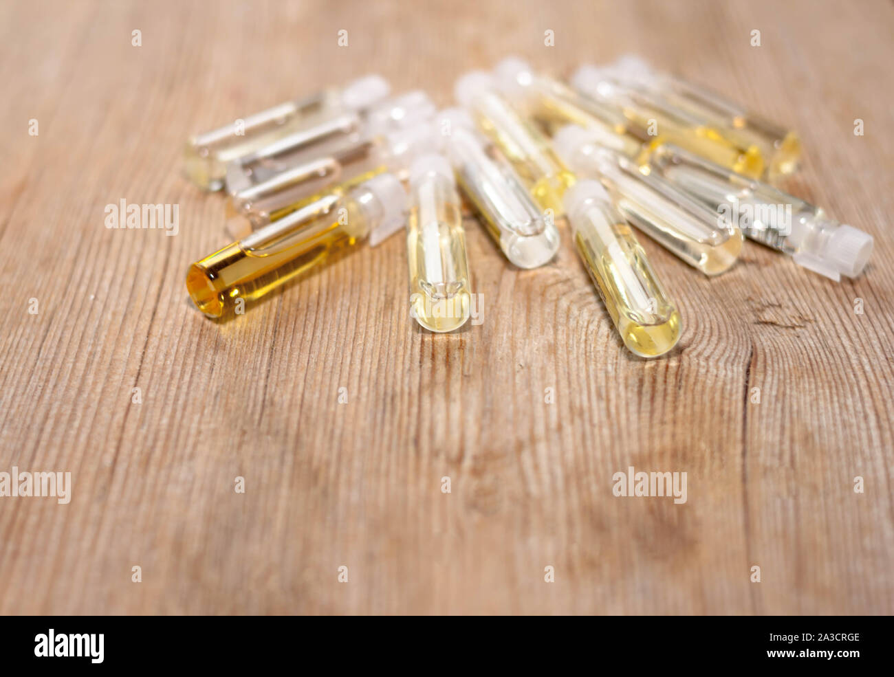 Group of small glass bottles on wooden background. Perfume testers or chemical samples. Side view. Selective soft focus. Shallow depth of field. Text Stock Photo