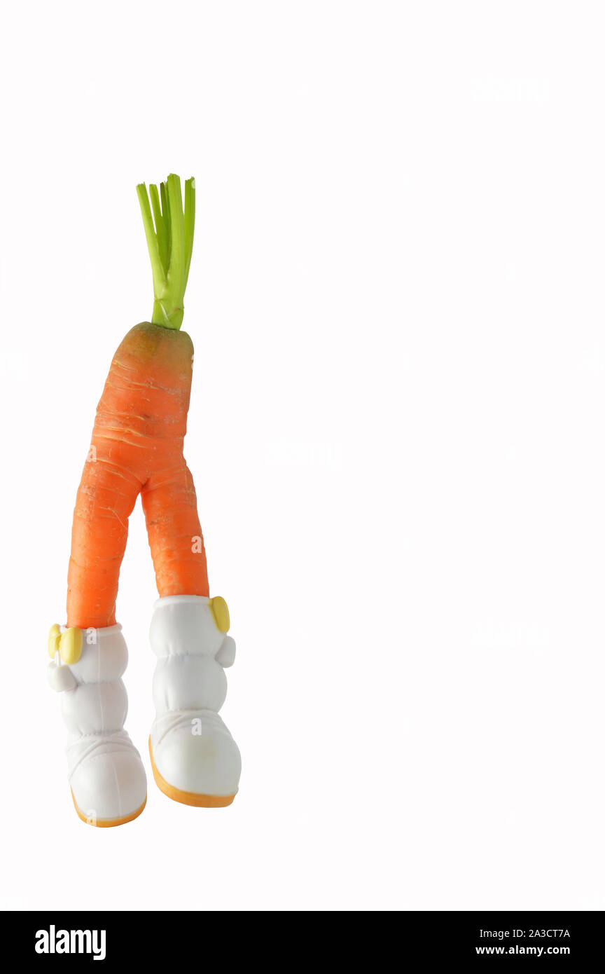 Funny shaped carrot with doll boots on white background Stock Photo