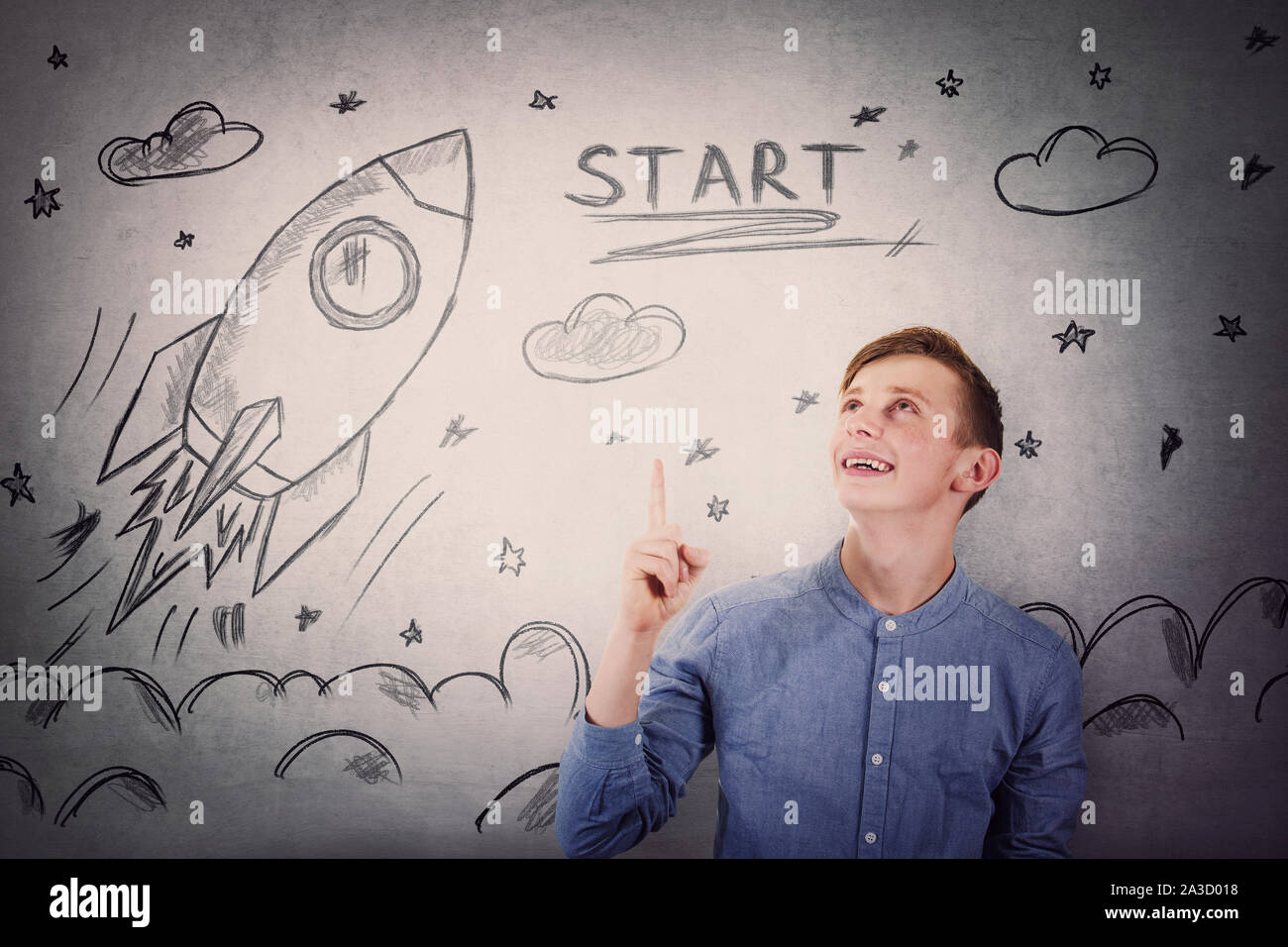 Joyful student guy pointing finger and looking up, happy face expression, showing rocket ship startup sketch, taking off in space. Stock Photo