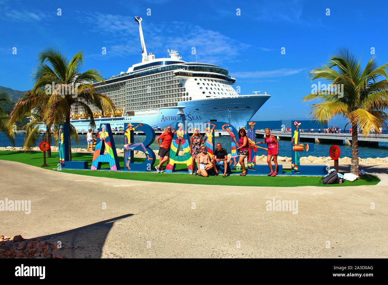 Tourists pose for photos in front of the Royal Caribbean Anthem Of The Seas cruise ship, on the Royal Caribbean privately owned resort of Labadee. Stock Photo
