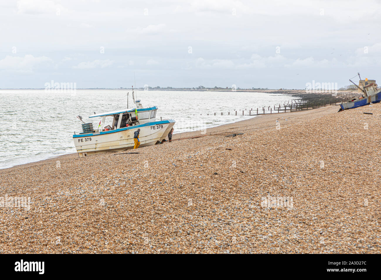 Fishermen winching their boat up a shingle beach Stock Photo