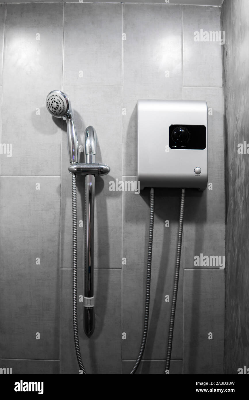 Instant tankless electric water heater installed on grey tile wall with