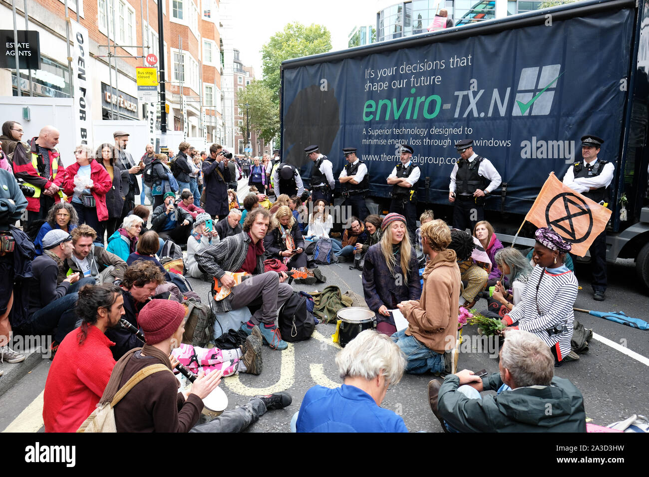 Westminster, London, UK - Monday 7th October 2019 - Extinction Rebellion XR climate protesters block Marsham Street directly outside the Home Office - the protesters parked a lorry across the road and several have then glued themselves to the vehicle - Police watch on as protesters play music. Photo Steven May / Alamy Live News Stock Photo