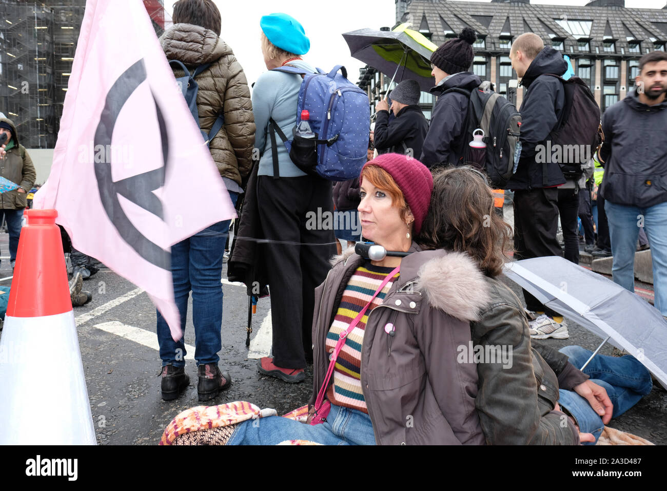 Westminster, London, UK - Monday 7th October 2019 - Two Extinction Rebellion XR protesters have locked their necks together and sit in the drizzle on Westminster Bridge.  Photo Steven May / Alamy Live News Stock Photo