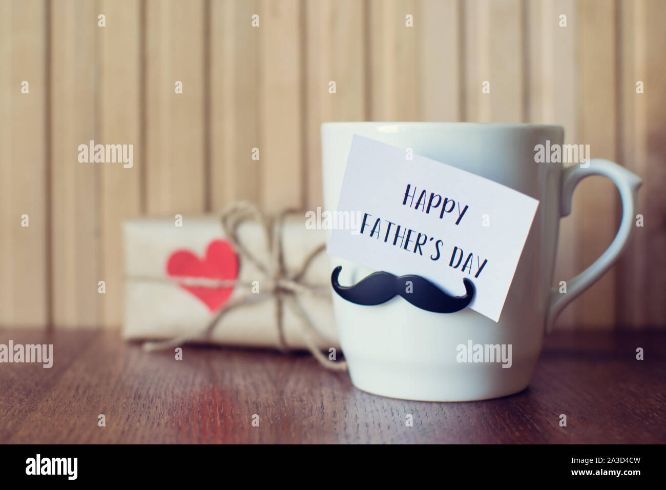 Fathers day. Greeting Message, Cup with funny mustache over wooden board. Stock Photo