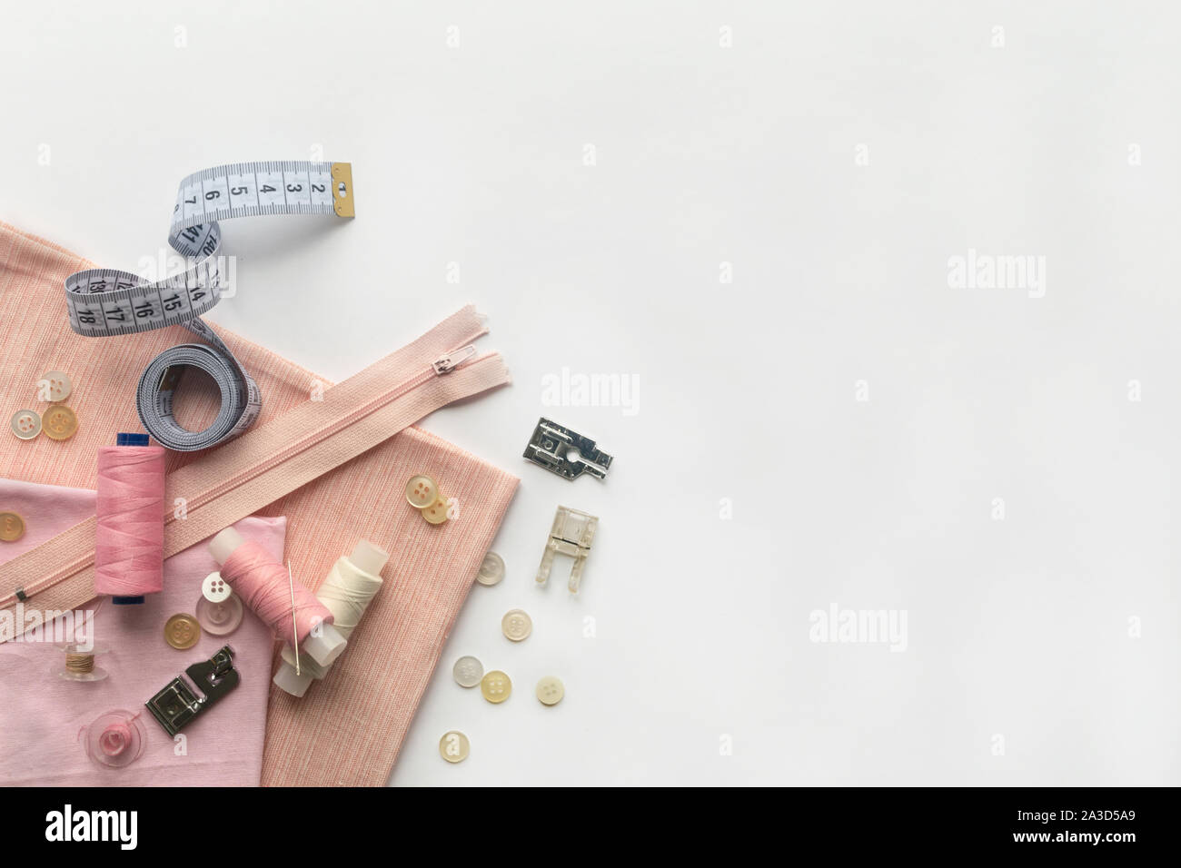 Sewing accessories and fabric on a white background. Needles, buttons, fabric, sewing threads and sewing centimeter. top view, flatlay Stock Photo