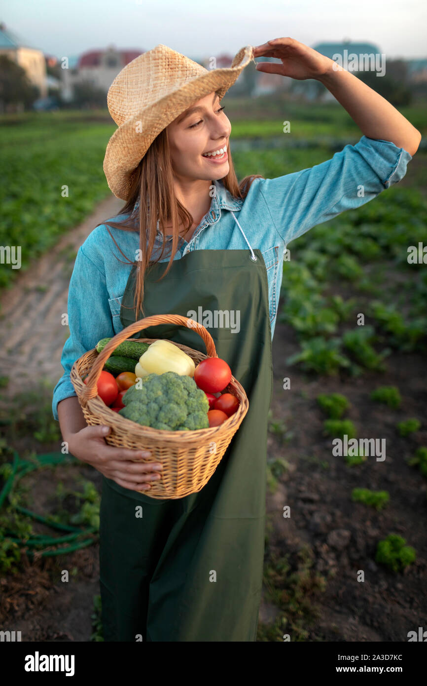 Young farmer girl has delivered fresh vegetables to the customer and greets him Stock Photo