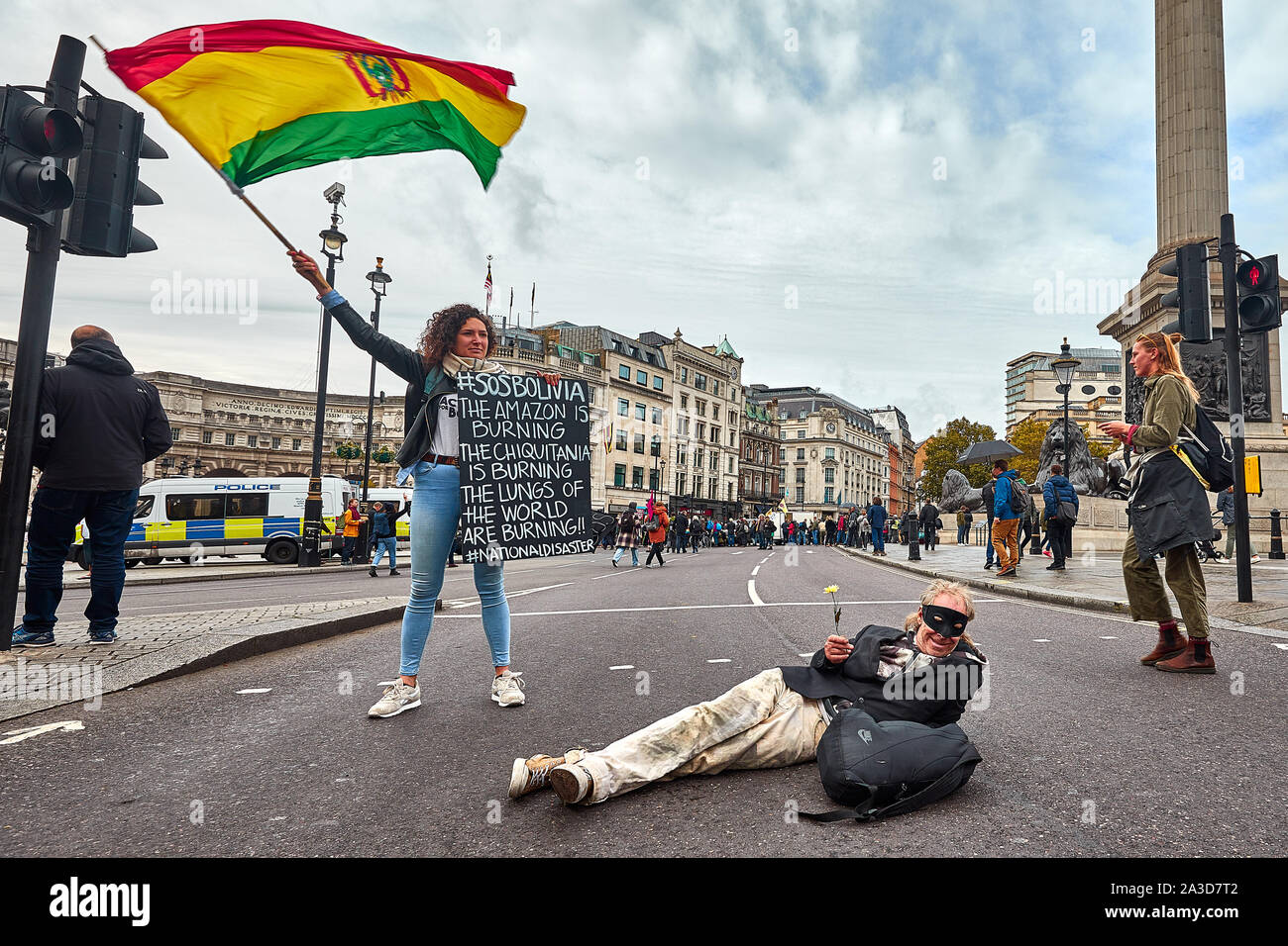London, U.K. - Oct 7, 2019: An environmental campaigner from Extinction Rebellion protests in Trafalgar Square about deforestation in Bolivia, joined by another protestor blocking the highway. Stock Photo