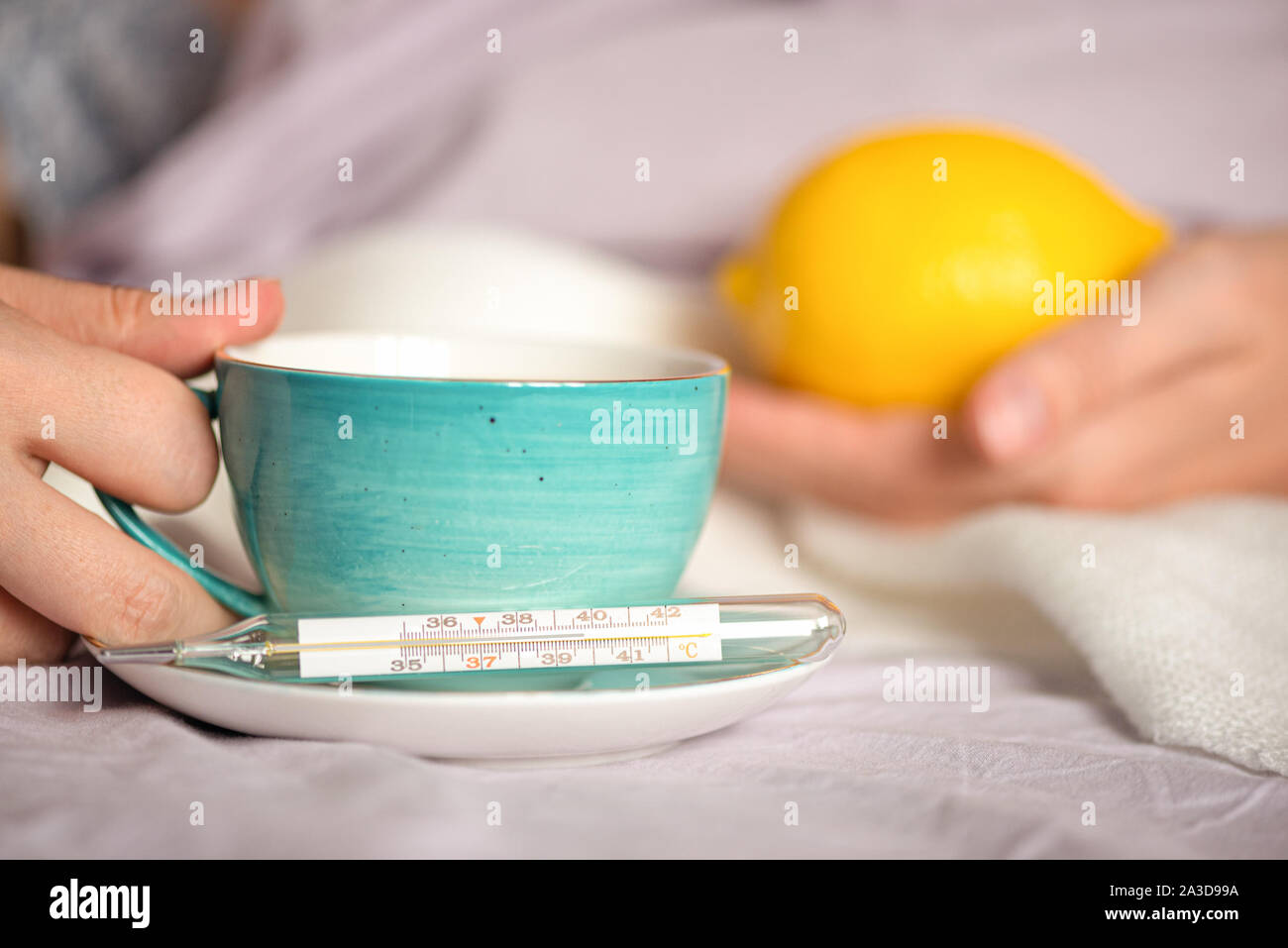 Flu sick woman drinking a hot tea with lemon juice. Stock Photo