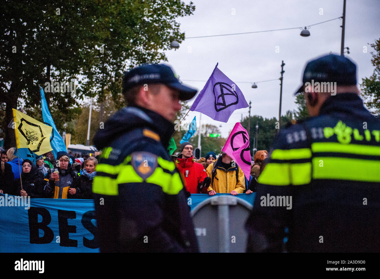 Two Dutch cops speak before the protesters holding a banner and flags during the demonstration.For 2 weeks, Extinction Rebellion and allied movements will gather in major cities across the globe and continue to rebel against the world’s governments for their criminal inaction on the Climate and Ecological Crisis. XR climate activists in Amsterdam are going to organize a large-scale blockade lasting several days on the Museumbrug, in front of the Rijksmuseum. From early in the morning, hundreds of XR activists showed up on the bridge, where there was a visible police presence. The Environmental Stock Photo