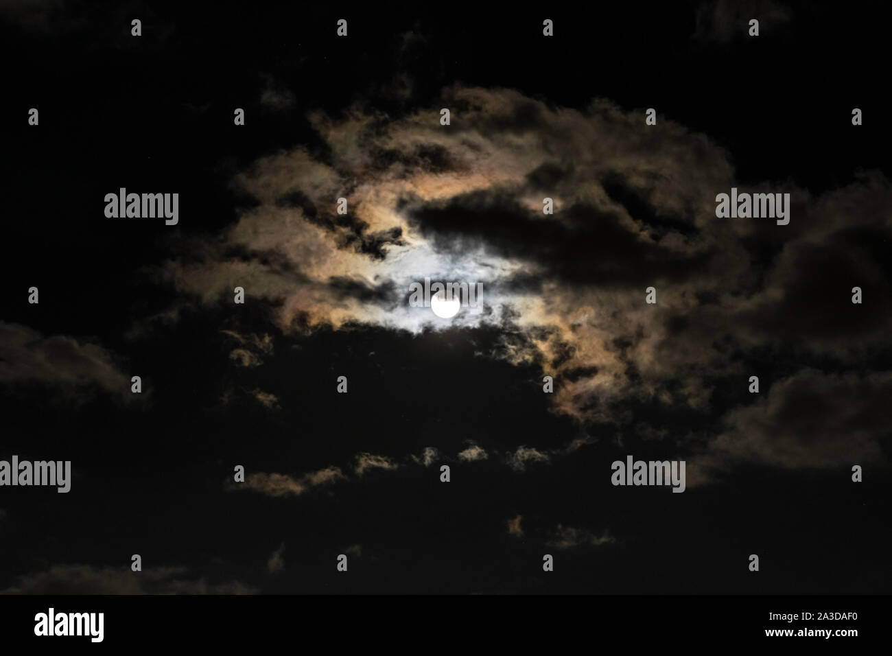 Full moon with clouds and colorful corona, also called aureole (optical phenomenon) Stock Photo