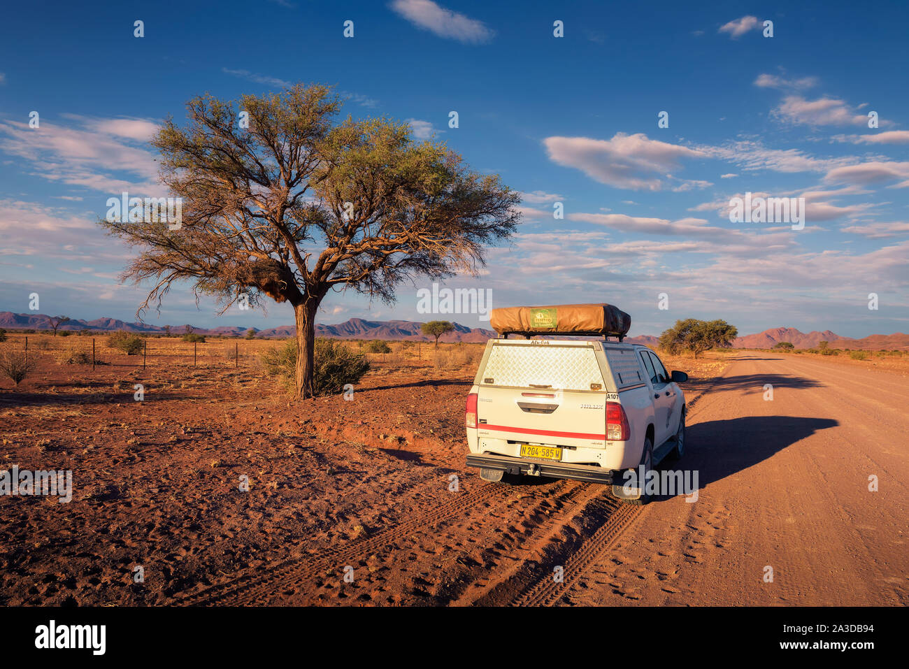 4x4 rental car equipped with a roof tent driving on a dirt road in Namibia Stock Photo