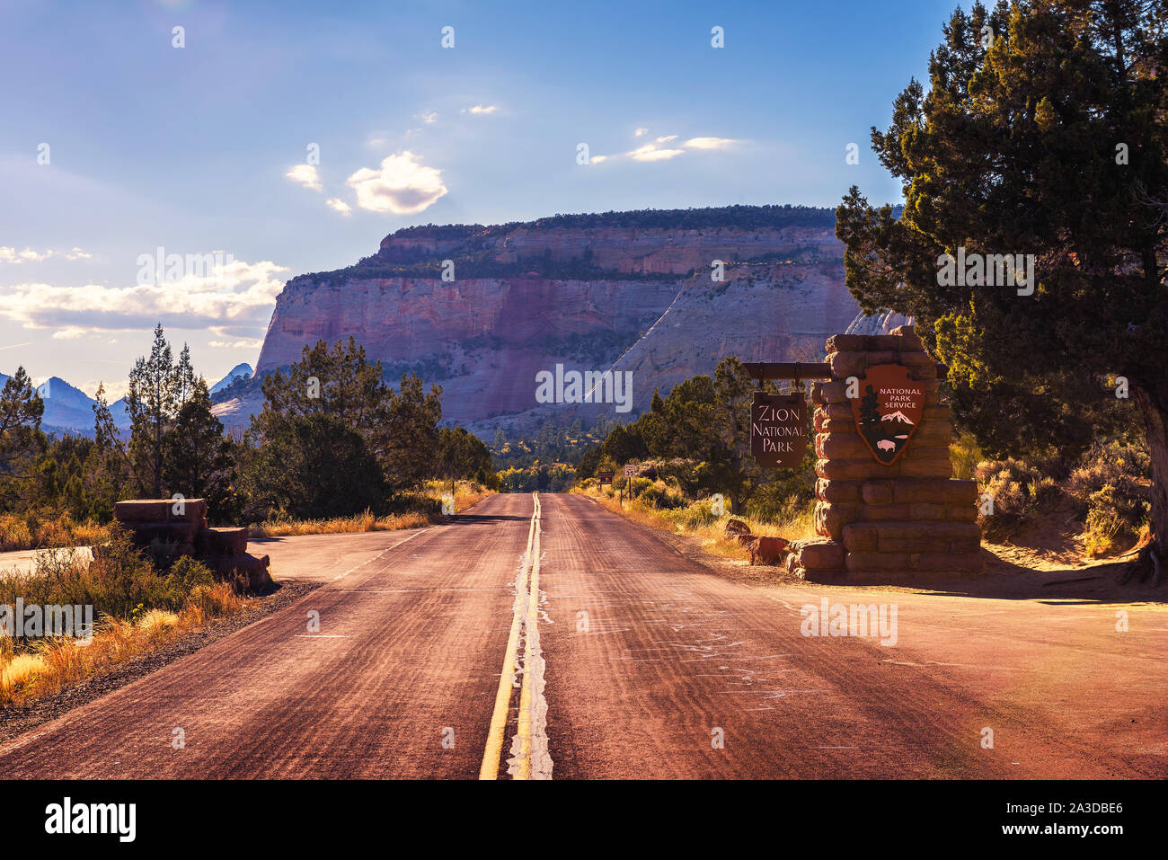 Road and welcome sign at the entrance to Zion National Park before sunset Stock Photo