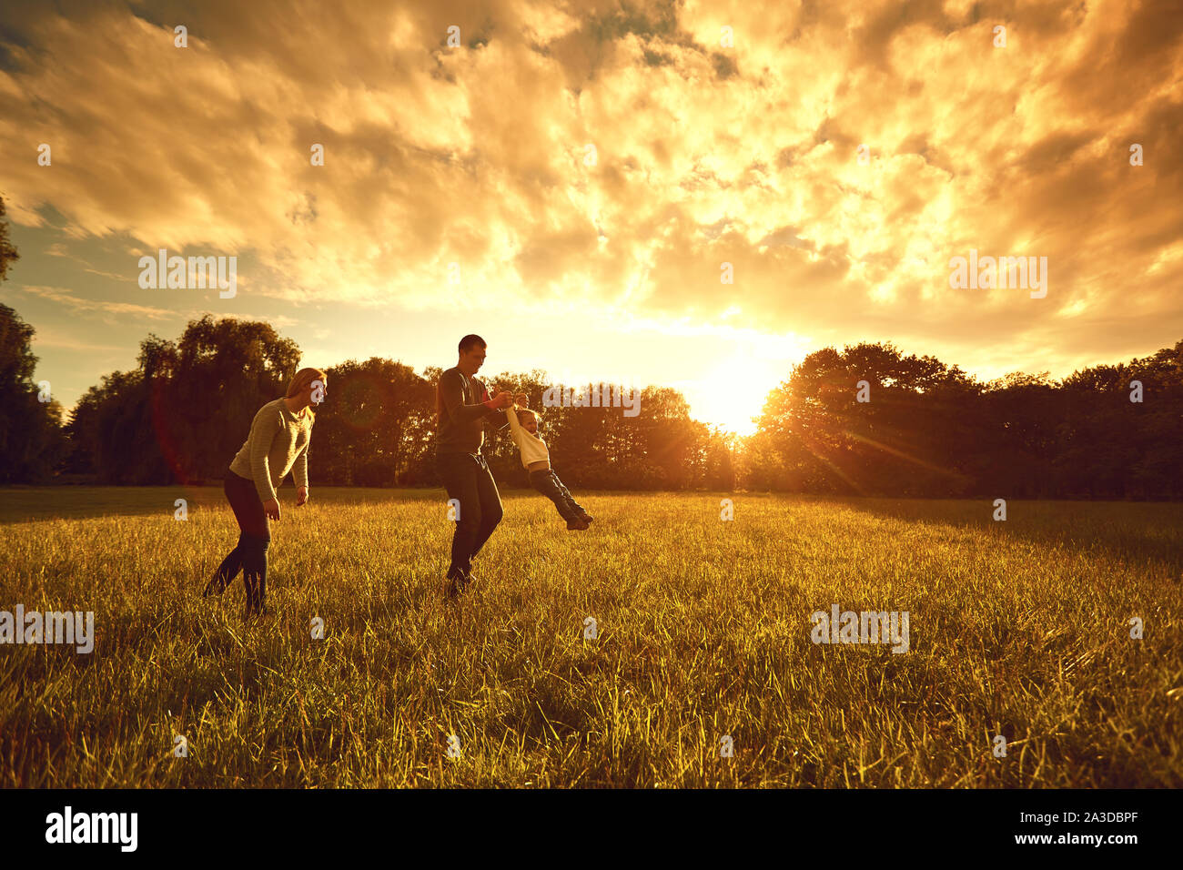 Happy family plays on the park at sunset. Stock Photo