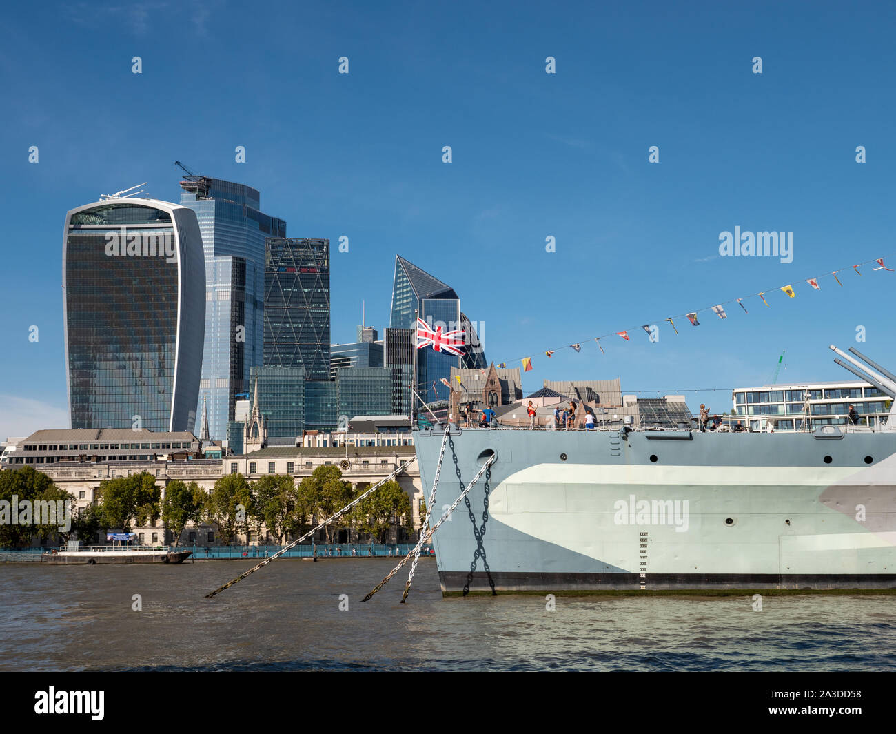 Modern skyscrapers in the City of London behind HMS Belfast on the river Thames, London, UK Stock Photo