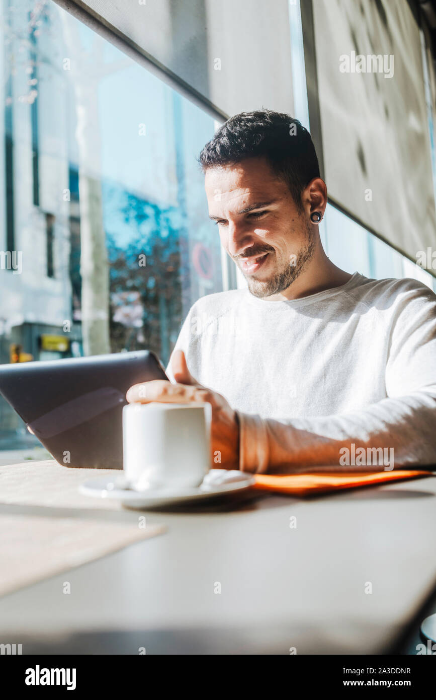Young man using tablet computer in cafe Stock Photo