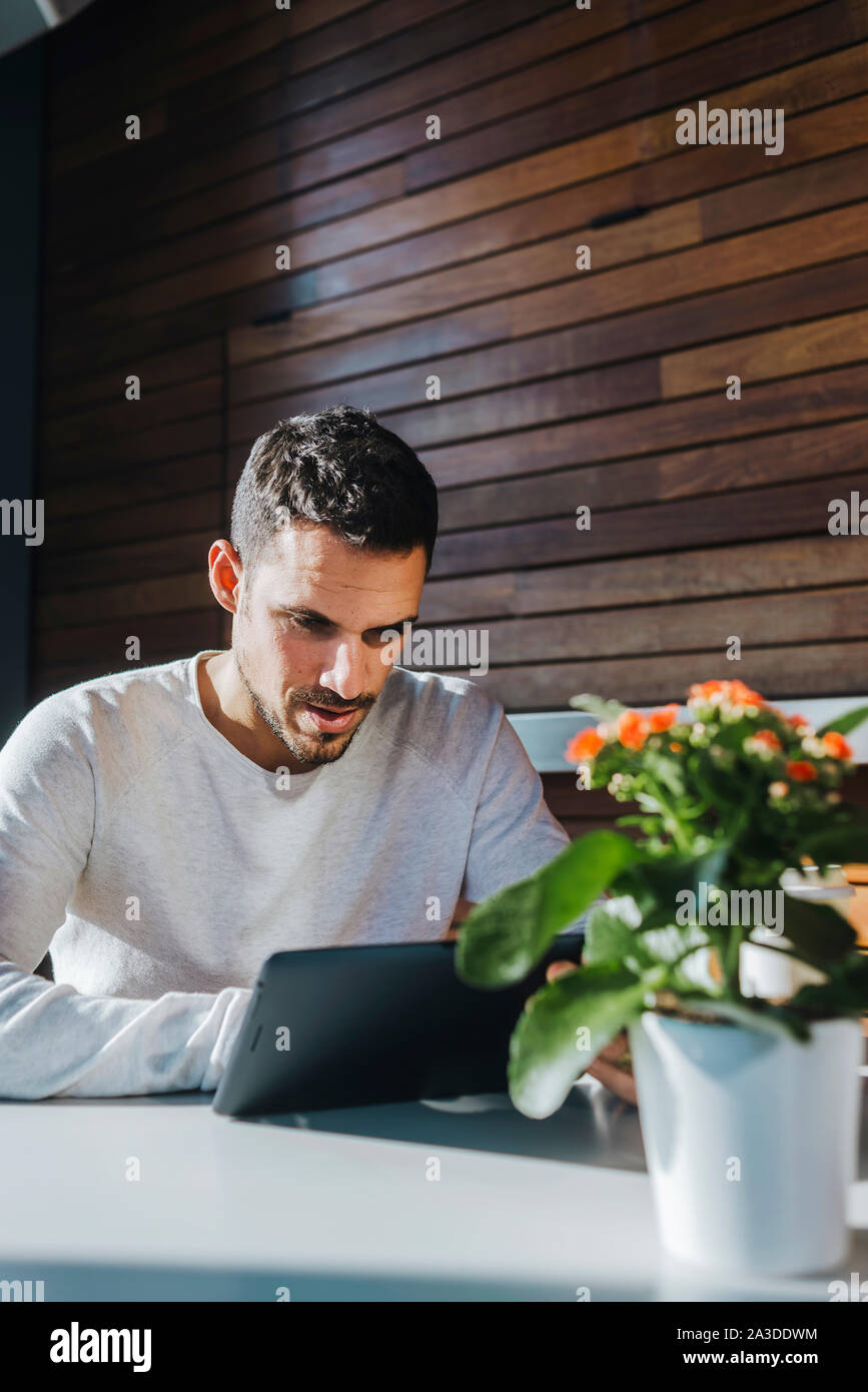 Stylish young man sitting on couch in a cafe using tablet Stock Photo