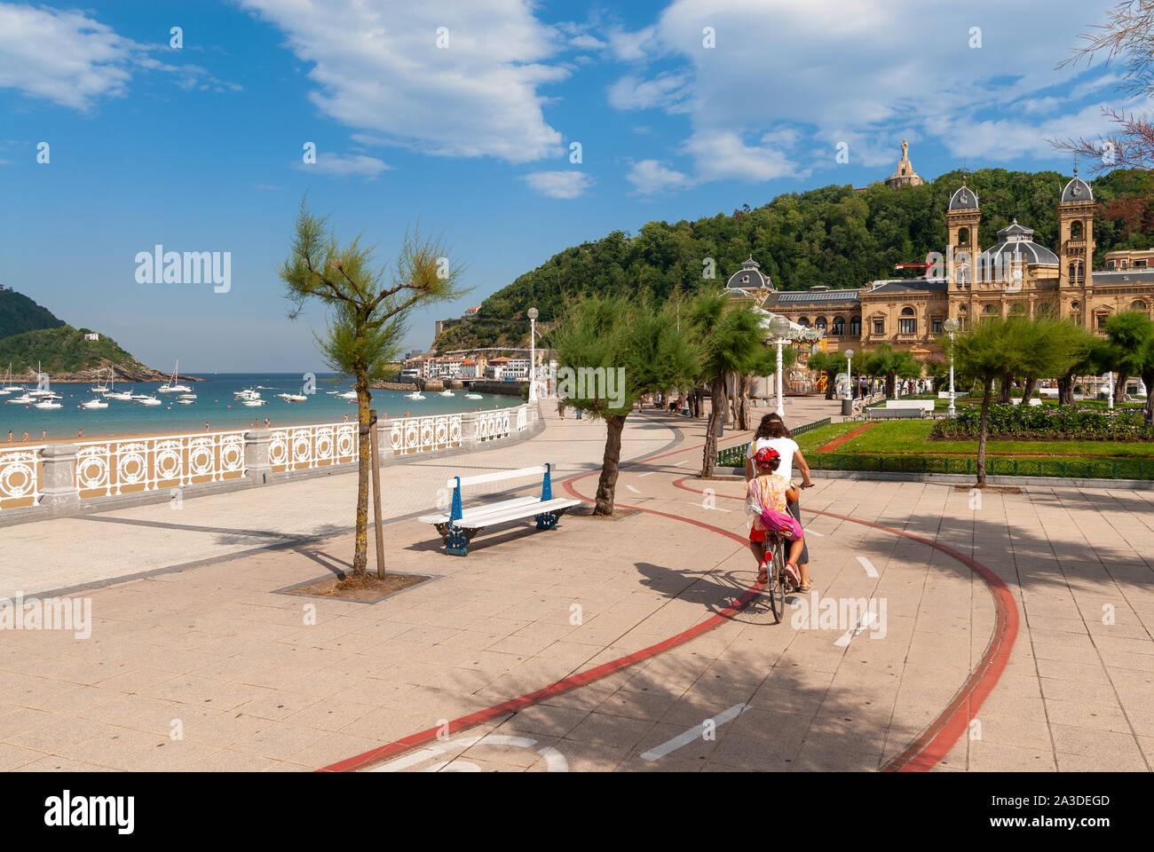 Woman  and child cycling along the cycle path beside the Playa de La Concha, San Sebastian, Basque Country, Spain Stock Photo