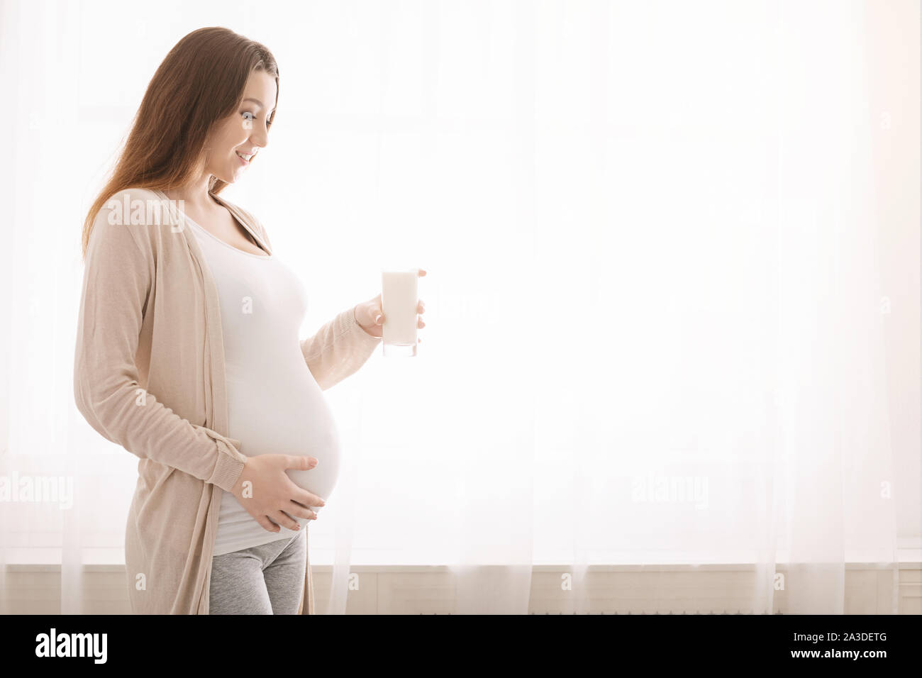 Young pregnant woman holding glass of fresh milk Stock Photo