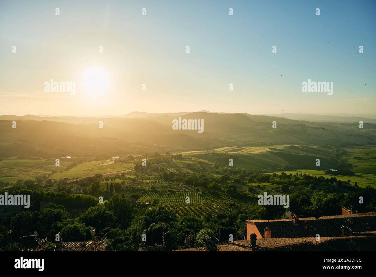 Aerial view of beautiful scenic hill landscape with green summer forests fields buildings and sun in Tuscany region of Italy Stock Photo