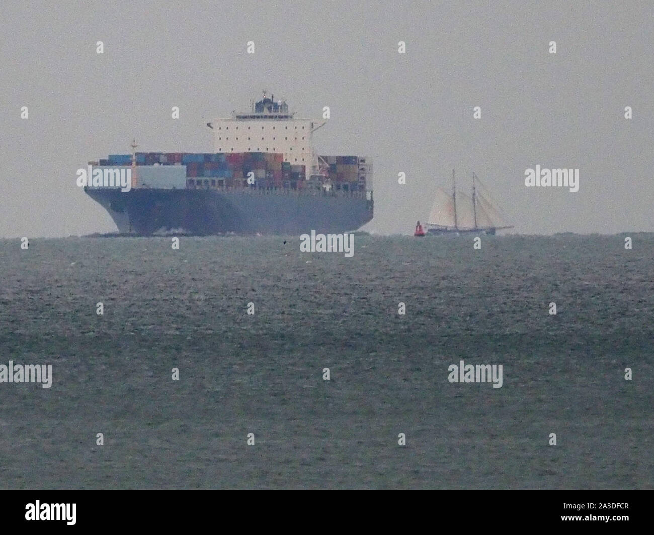 Sheerness, Kent, UK. 7th October, 2019. Historic sailing ship De Gallant seen sailing  passing Sheerness, Kent just before nightfall this evening in foul weather before anchoring overnight. De Gallant is transporting a special cargo of wine, coffee, spices and more to London. It’s thought to be the first major cargo arriving by sail since the 1960s. Pictured: seen crossing the path of modern containership SM Charleston. Credit: James Bell/Alamy Live News Stock Photo