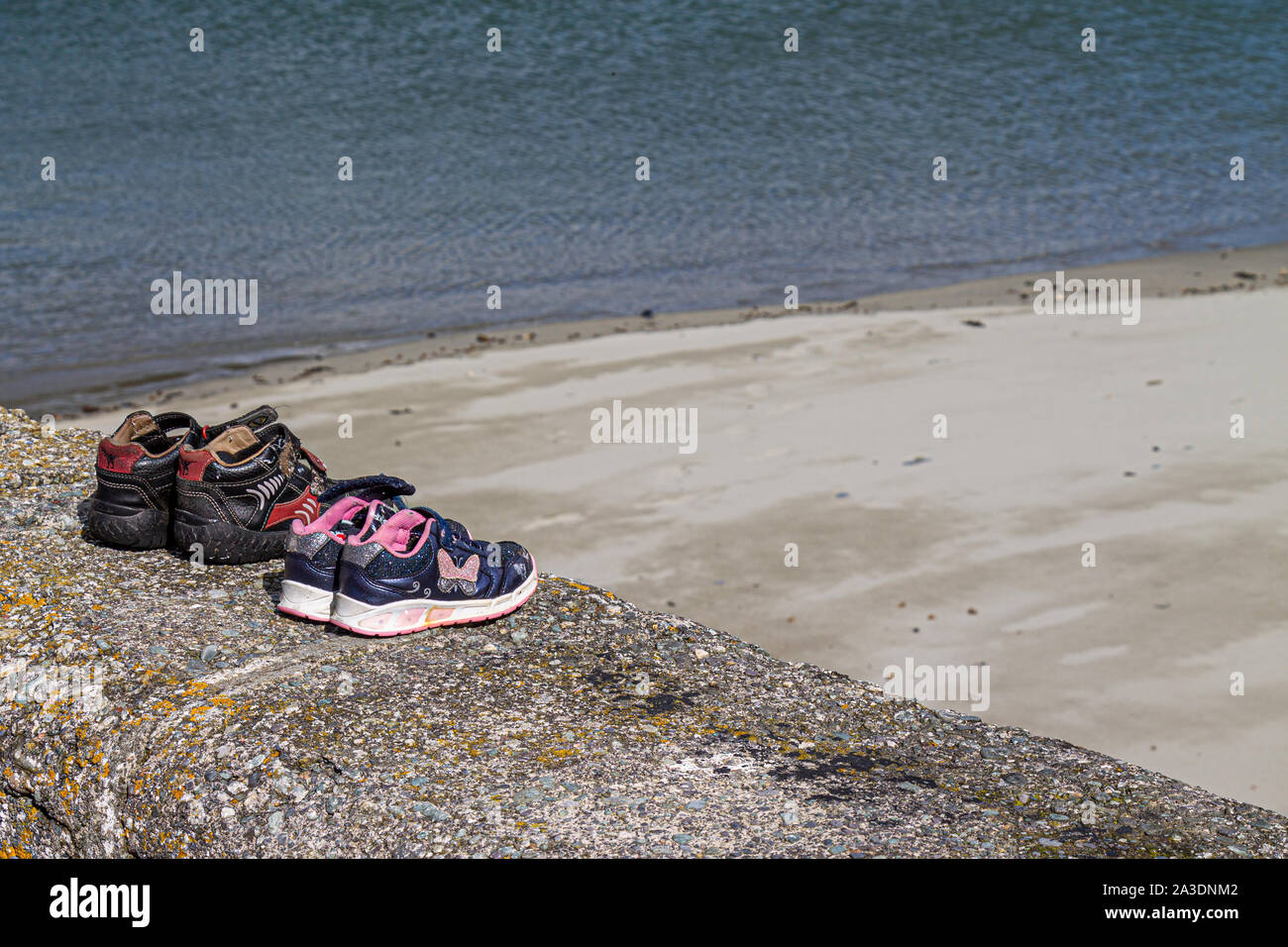 childrens training shoes left on a sea wall Stock Photo