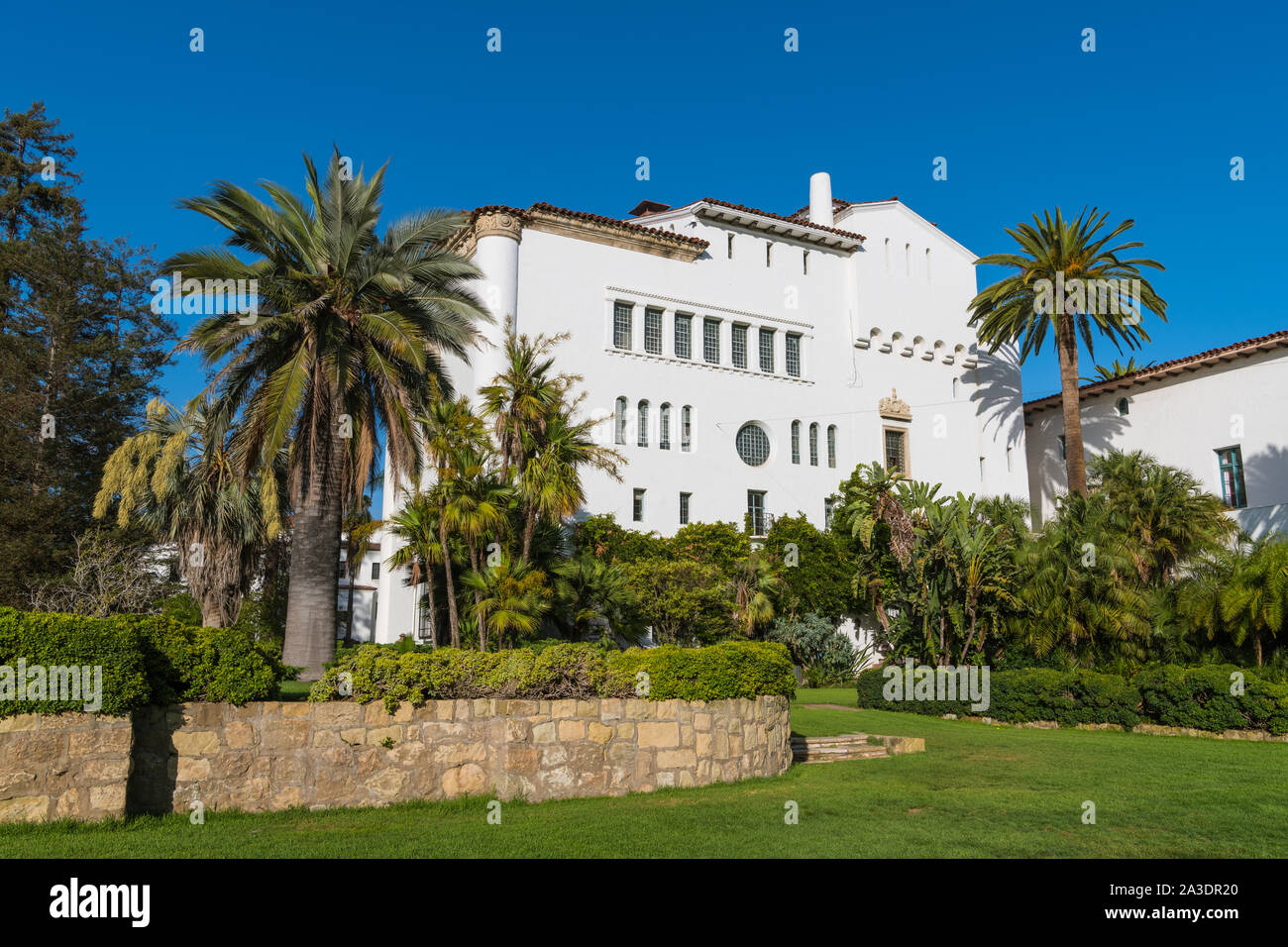 A beautiful white building in the Spanish architectural style in lush tropical gardens in the Santa Barbara County Courthouse complex - Santa Barbara, Stock Photo