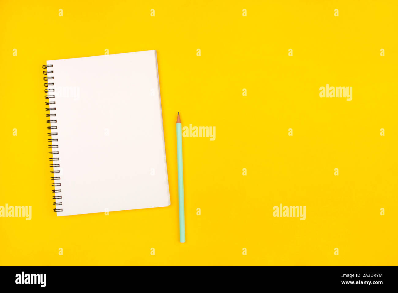 Empty notebook and pencil on yellow background, top view. Stock Photo
