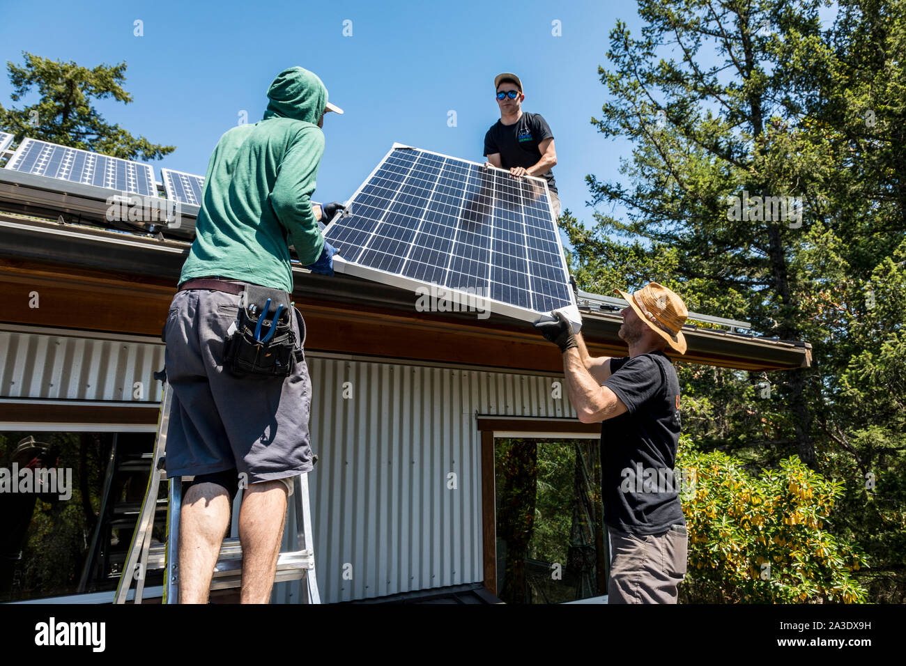 Workers install solar photovoltaic panels on a homeowners roof in