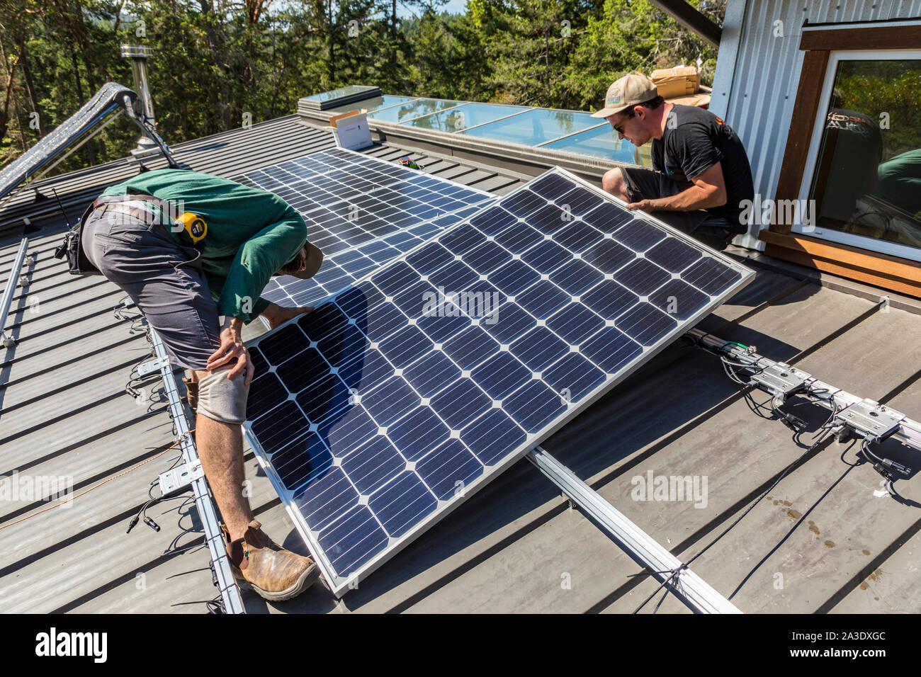 Workers install solar photovoltaic panels on a homeowners roof in