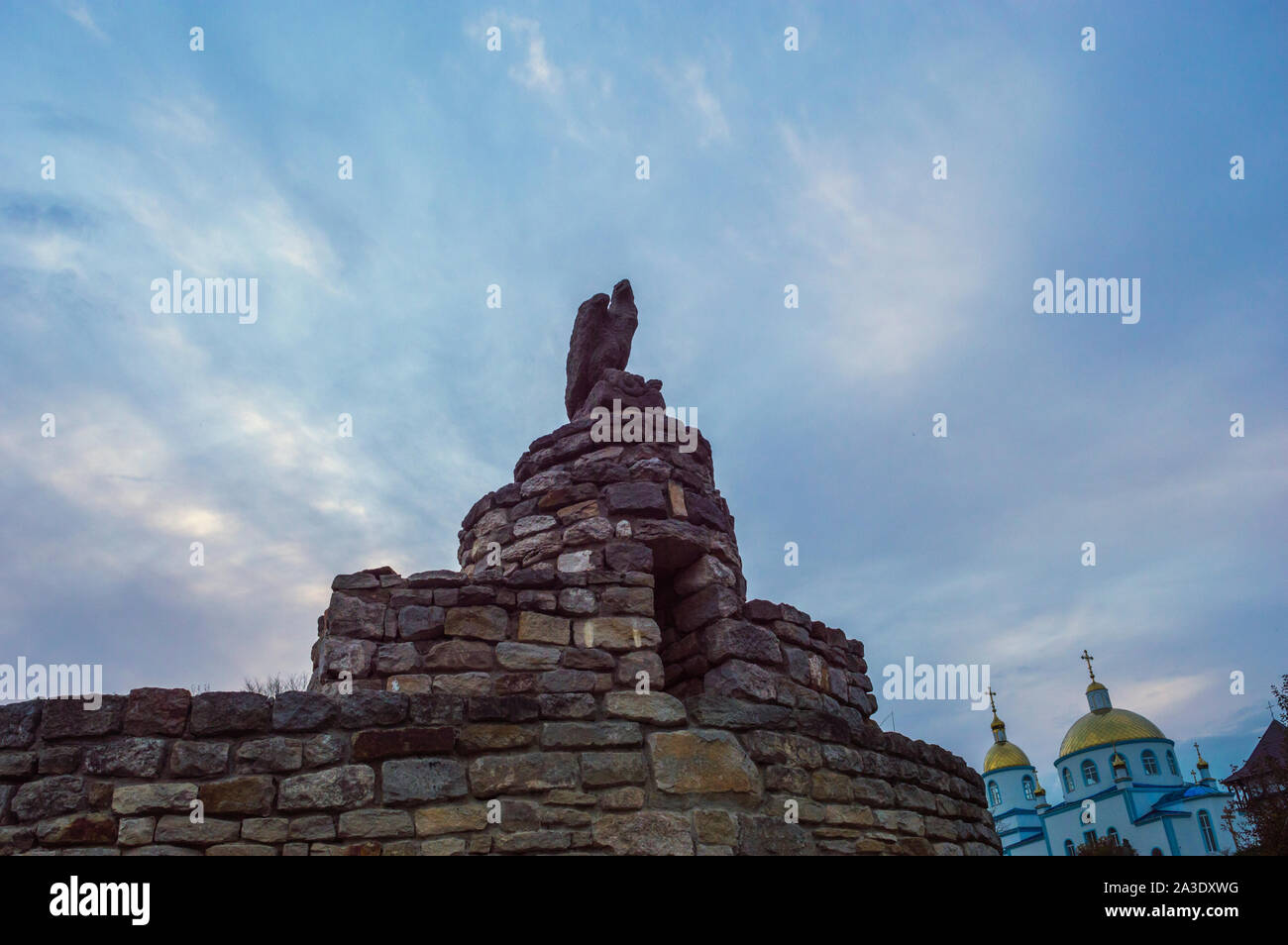 Eagle Sculpture on Top of Medieval Stone Wall  on Background fo Blue Sky Stock Photo