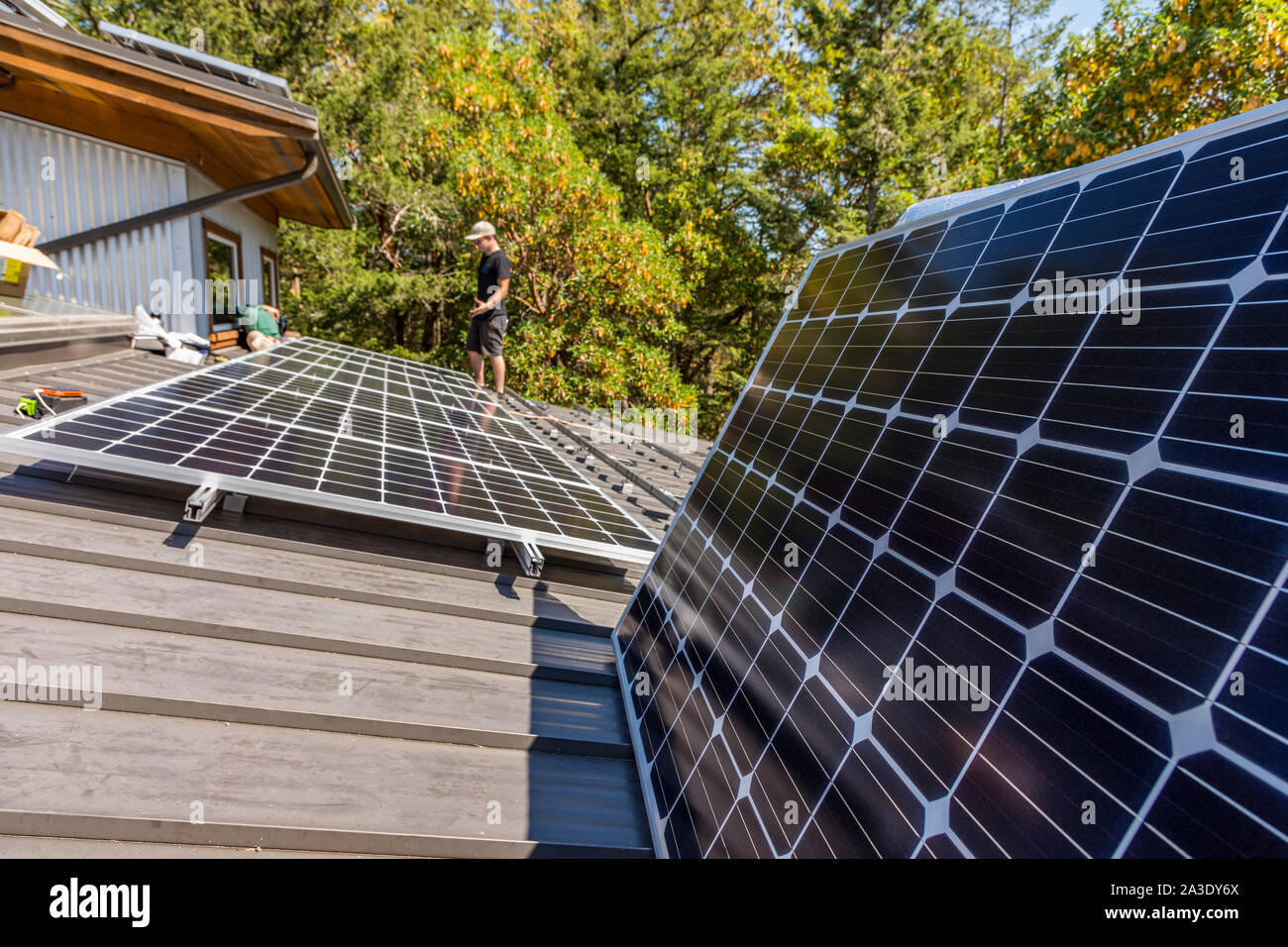 Workers install solar photovoltaic panels on a homeowners roof in
