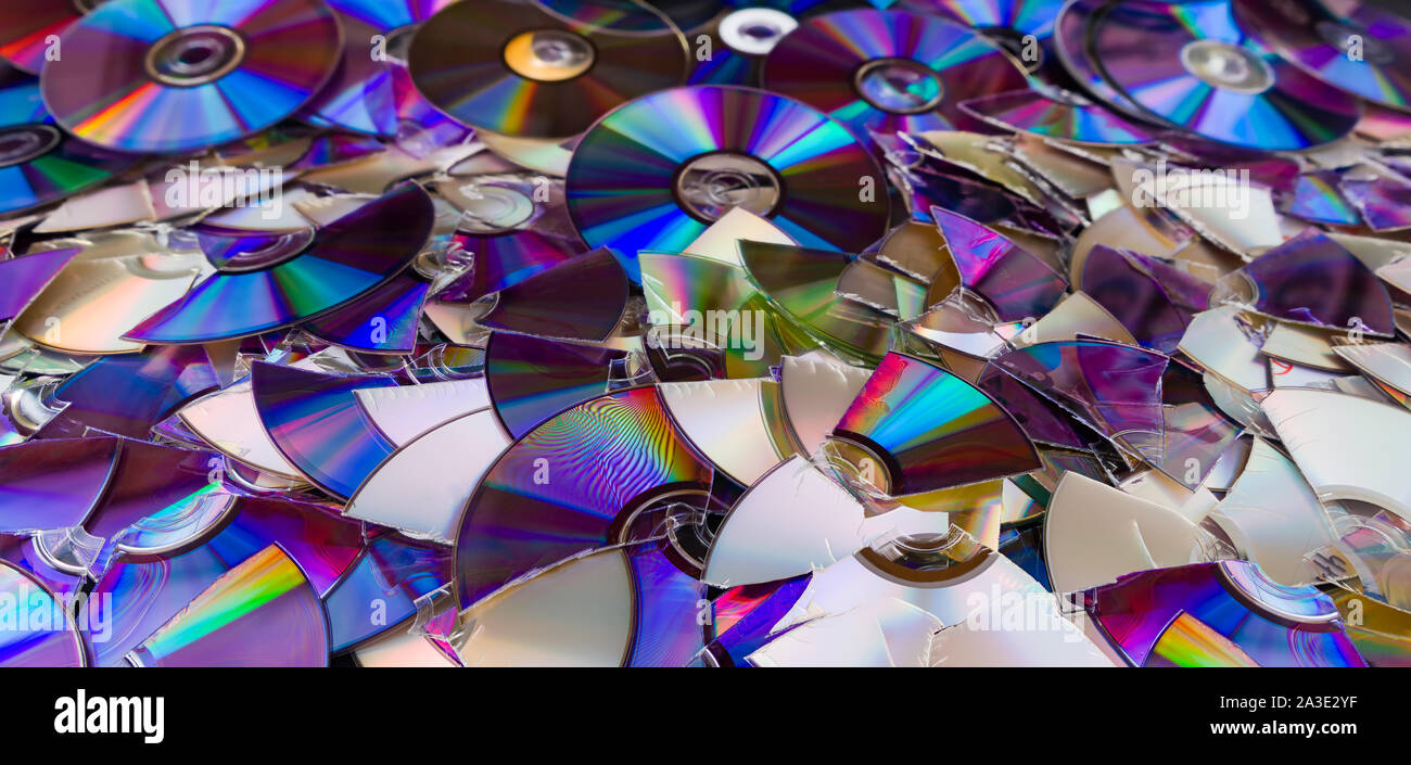 Broken compact discs. Colorful texture detail of obsolete digital media. Data backup, archiving or eco disposal. Damaged storage devices. E-aste heap. Stock Photo