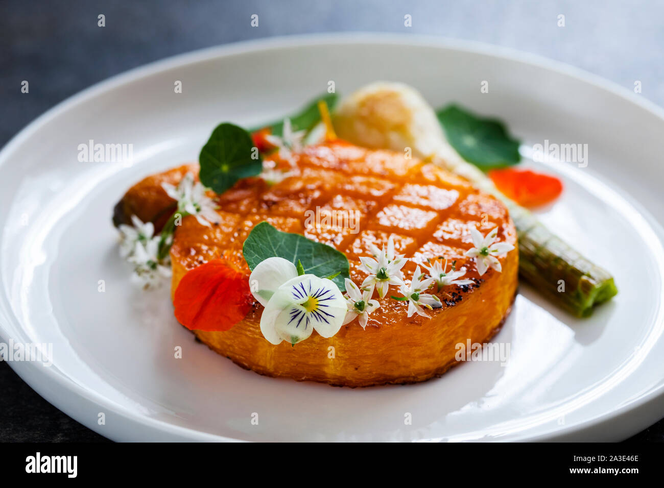 Roast pumpkin dish with leek and garlic flowers Stock Photo