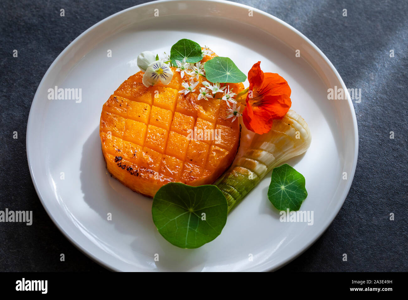 Roast pumpkin dish with leek and garlic flowers Stock Photo