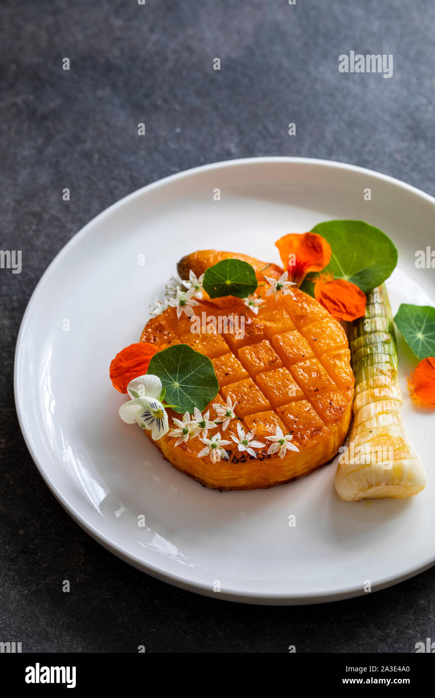 Roast pumpkin dish with leek and garlic flowers Stock Photo