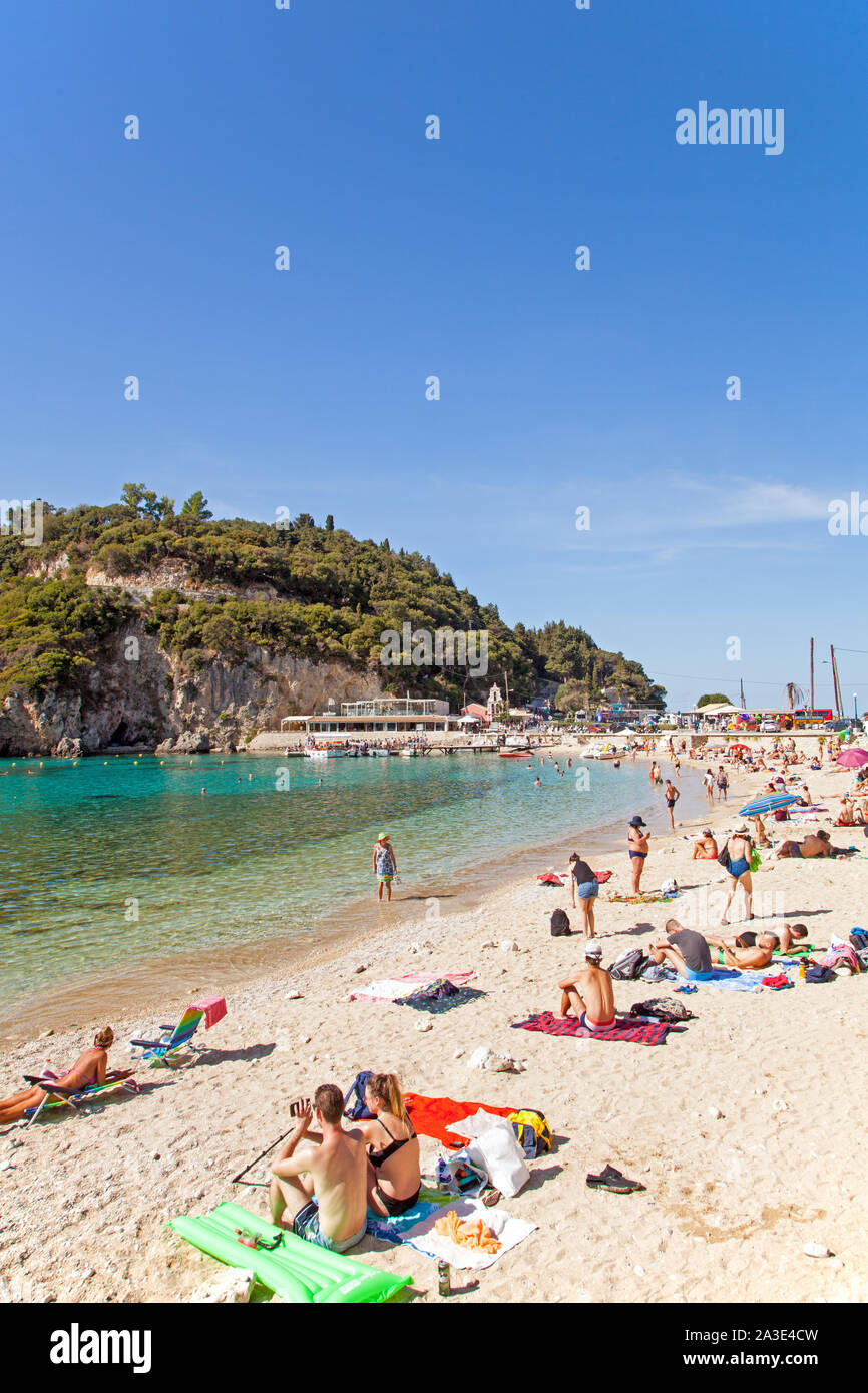 Holidaymakers and tourists enjoying the sunshine on the sandy beach at the Greek holiday resort of Paleokastrita on the Island of Corfu Greece Stock Photo