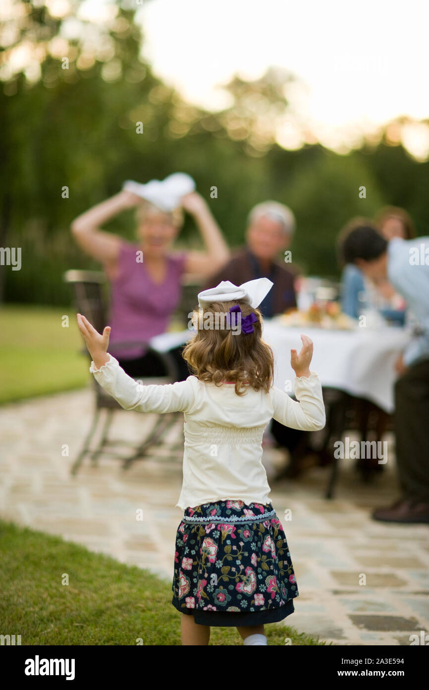 Young girl with a napkin on her head outside with her family. Stock Photo